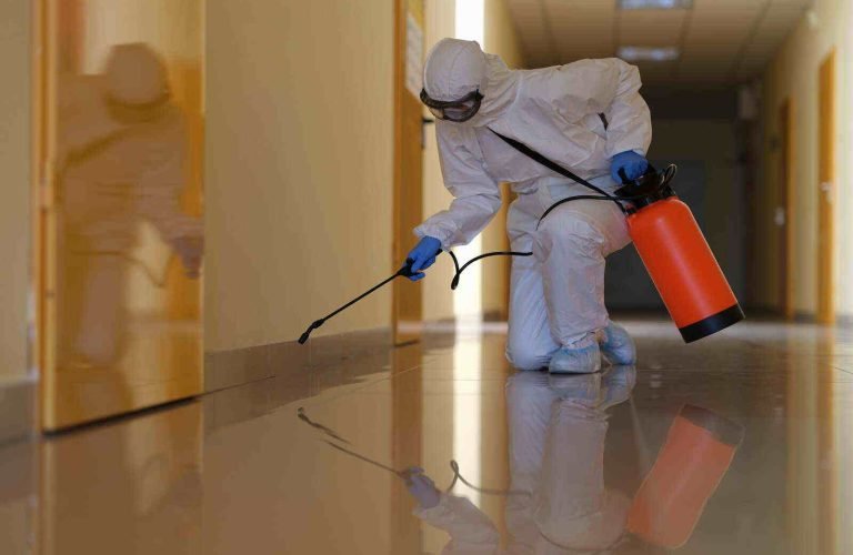 Person in protective suit disinfects office and corridors to prevent spread of COVID-19. Disinfection of premises in medical institutions concept